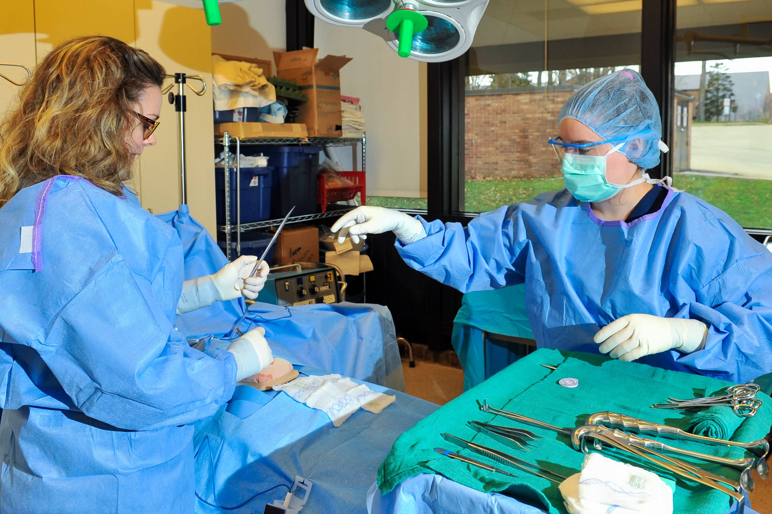 two students in scrubs practicing surgery